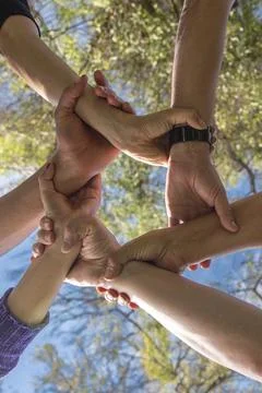 Low angle perspective of happy diverse people standing in a circle showcasi.. Stock Photos