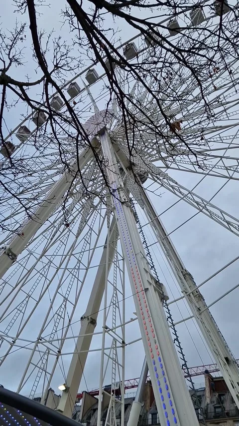 A low-angle perspective of the massive Grande Roue de Paris Ferris wheel spinnin Stock Footage 325081177