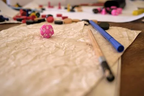 Low angle perspective of a pink 20 sided dice (d20) on a role paying game table Stock Photos