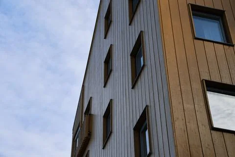 A low-angle perspective shot of a modern multi-story residential building fea Stock Photos