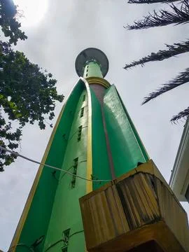 Low-angle perspective of a tall green minaret reaching the cloudy sky Stock Photos