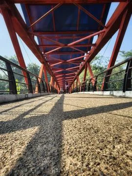Low angle perspective view of a red steel pedestrian bridge walkway Stock Photos