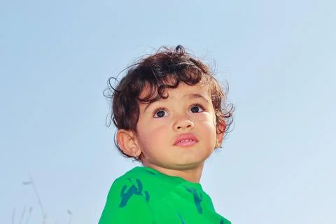 Low angle portrait of cute smart little Indian male child posing outside agai Stock Photos