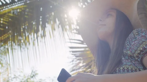 Low angle portrait of girl using mobile phone on tropical nature background Stock Footage 128751750