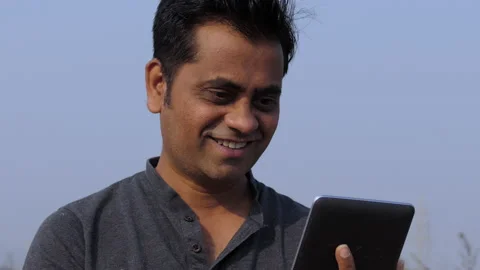 Low angle portrait shot of a middle aged happy indian man using a tablet smiling Stock Footage 148455945