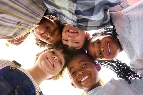 Low Angle Portrait Of Smiling Multi-Cultural Children Looking Down Into Camera Stock Photos