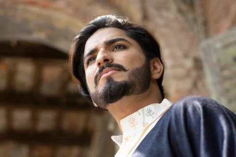 Low angle portrait of a young Indian man with ethnic wear in an old vintage h Stock Photos