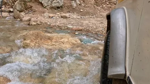 Low Angle POV Of 4x4 Vehicle Crossing Fast Flowing Rocky Mountain Stream Stock Footage 342726397