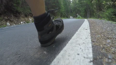 Low Angle POV of Hiking Boots Walking on Mountain Asphalt Roadside with Forest Stock Footage 344815220