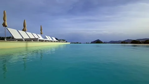 Low angle pov of infinity pool with deckchairs at sicilian hotel Stockbeeldmateriaal 279908622
