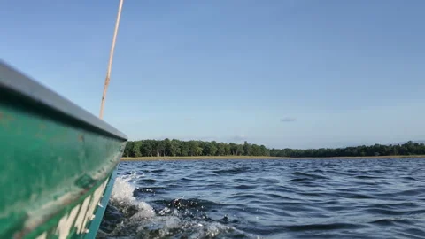 Low angle POV shot of green wooden boat hull sailing through water on sunny lake Stock Footage 340253953