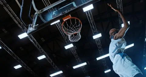 Low angle of professional basketball player in action performing slam dunk in a Stock Photos