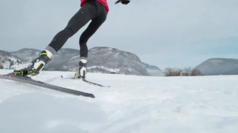 LOW ANGLE: Professional nordic skiing athlete pushes off her ski and poles. Stock Footage 165522220