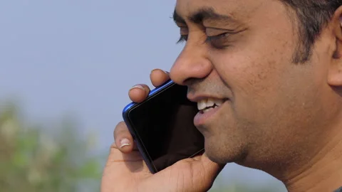 Low angle profile shot of a middle aged indian man happily talking over phone Stock Footage 148455955