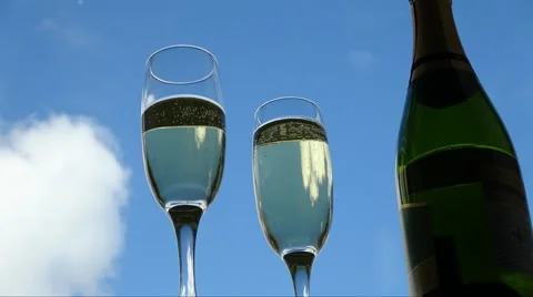 Low angle Prosecco poured into champagne flutes, time lapse blue sky with clouds Stock Footage 67420329