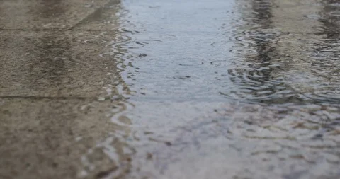 Low angle raindrops falling in deep puddles during rain storm. Stock Footage 118995169