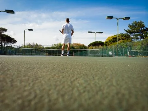 Low angle rear view of caucasian male tennis player playing on sunny outdoor Photos