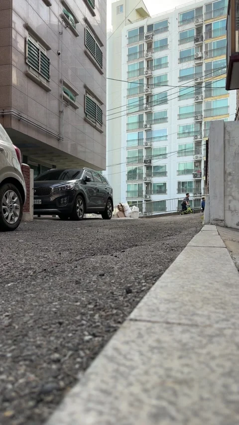 Low-Angle Residential Driveway Between Apartments and Parked Cars 스톡 동영상 340409995