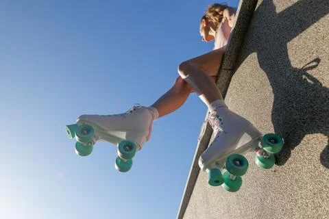 Low angle retro roller skates dangling from wall against blue sky summer li.. Stock Photos