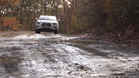 Low angle right slow motion of suv white car driving into water on a mud pat Stock Footage 123642702