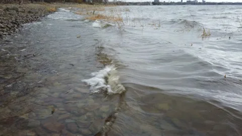 Low angle of river waves over reeds and shore line beach Stock-Footage 143197354