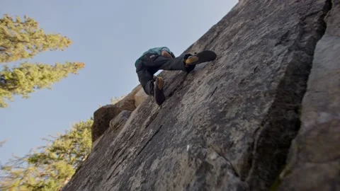 Low, up angle of rock climber climbing up boulder 库存影片 220306153