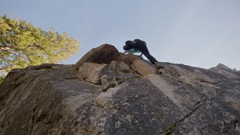 Low, up angle of rock climber climbing, topping out boulder 库存影片 220306170