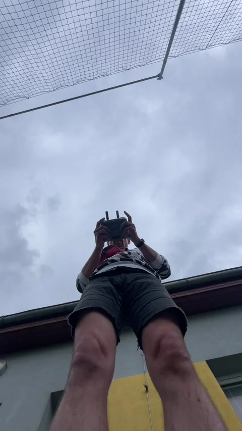 Low angle rooftop view of person holding remote controller against cloudy sky Stock Footage 344585886