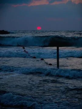 Low angle scenery view of a vivid red sunset under a cloudy sky on a blue wat 写真素材