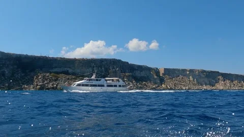 Low-angle sea-level view from sailing boat of touristic boat at favignana Stock Footage 278942710