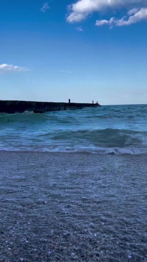 Low Angle Sea Waves Crashing on Beach with Pier in Background Stock-Footage 339726133
