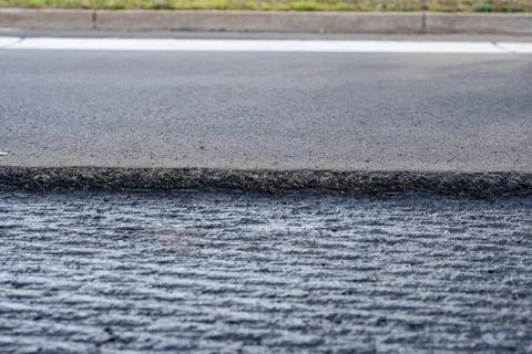 Low angle selective focus on asphalt overlay paving on top of a concrete base of Stock Photos