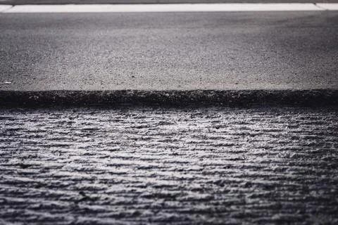 Low angle selective focus on asphalt overlay paving on top of a concrete base of Stock Photos