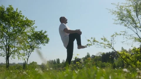 Low angle senior man pulling knee to chest during fitness routine Video stock 334868249