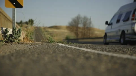 Low angle shallow depth of field of country road with cars passing 動画素材 64796392