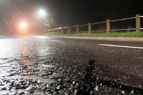 A low angle, shallow depth of field of tarmac highlighted by street lights. Stock Photos