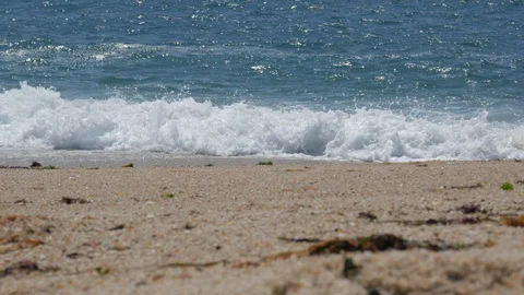 Low angle, shallow focus shot of waves breaking on bright sandy beach 스톡 동영상 111703457