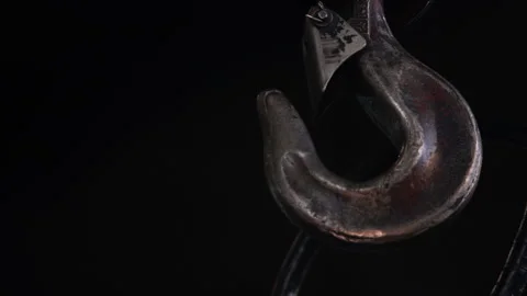 Low angle shop hook swings against dark background 스톡 동영상 101046013