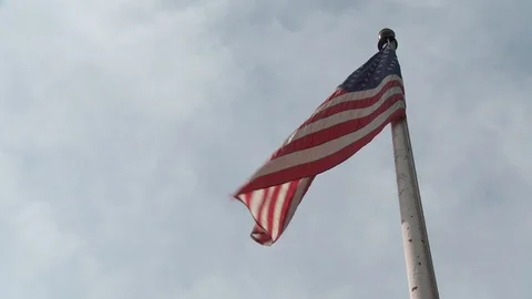 Low angle shot of American flag on flag pole with view of sky and clouds, day. Vídeo Stock 110917518