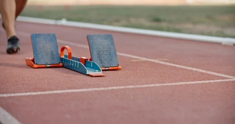Low angle shot of an athlete putting feet on starting blocks on stadium track 動画素材 118714716