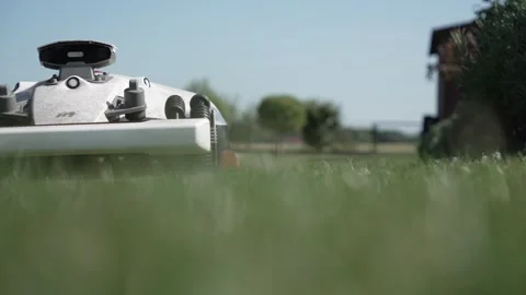 Low Angle Shot of Autonomous Robotic Lawn Mower Cutting Grass on a Sunny Day Stock Footage 345049651