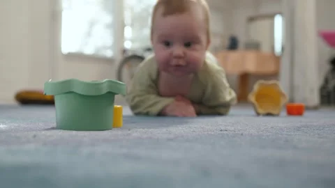 Low-angle shot of baby crawling toward colorful toys on carpet Stock Footage 339199503