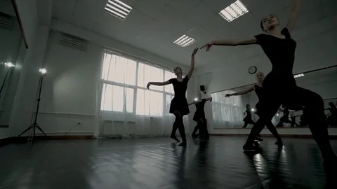 Low angle shot ballerinas dressed in the black leotards whirl. Ballerinas make a Video stock 113529922