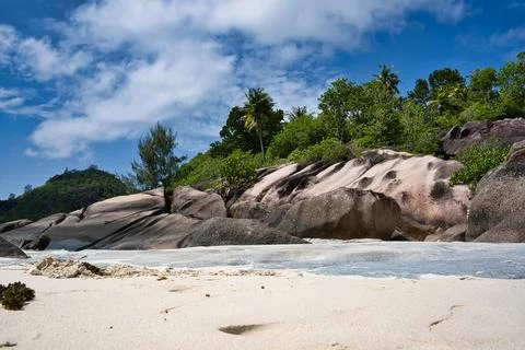 Low angle shot of beach, rock boulders and lush vegetation 2 Stock Photos