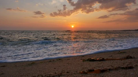 Low angle shot on beach at sunset with orange reflections on water Stock Footage 112003956