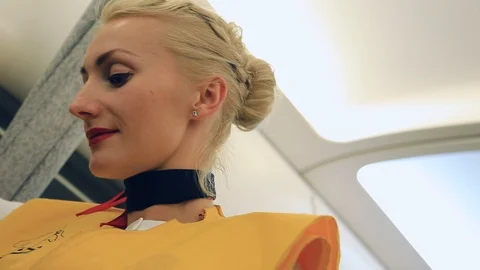 Low angle shot of beautiful elegant blonde stewardess demonstrating passengers 스톡 동영상 105272994