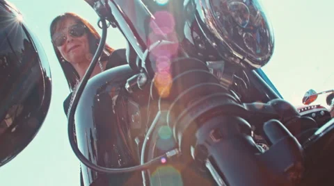 Low angle shot of a biker lady wearing sunglasses and sitting on her motorcycle Stock Footage 68638922