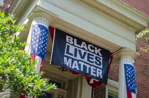 Low angle shot of a Black Lives Matter banner on a building with American flags Stock Photos