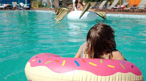 Low angle shot of blue swimming pool water and girl splashing while holding onto Stock Footage 65829498