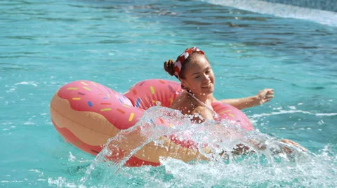 Low angle shot of blue swimming pool water and girl splashing while holding onto Stock Footage 66347191